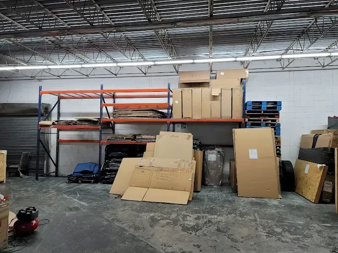 Warehouse interior with shelves, cardboard boxes, and pallets.