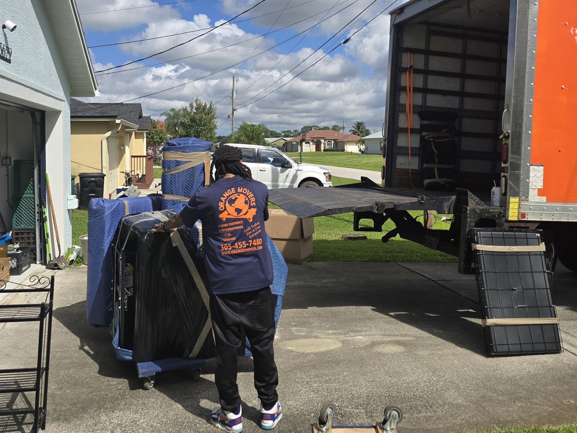 Man loading wrapped furniture into a moving truck on a sunny day.