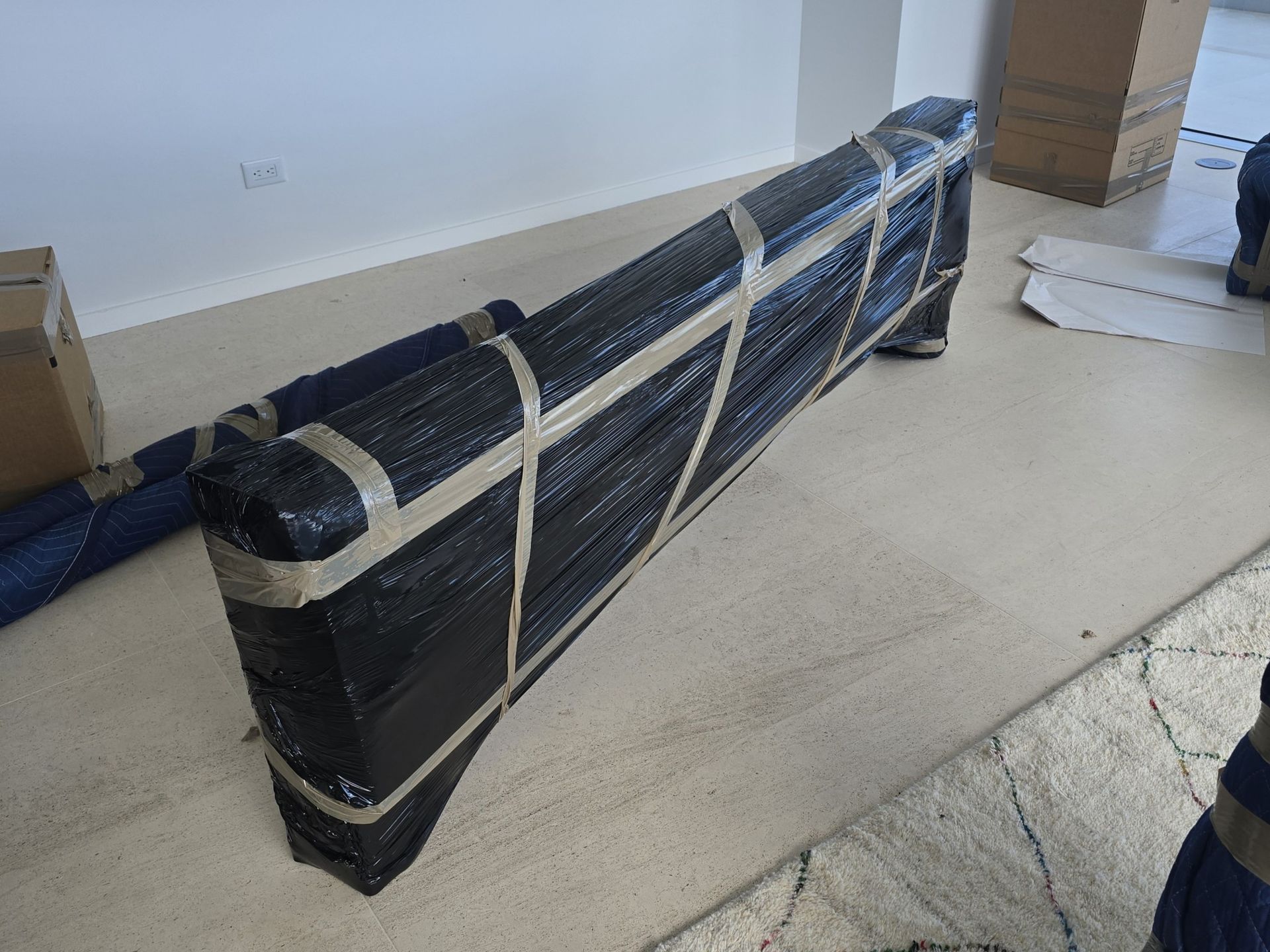 Wrapped black furniture secured with tape on a concrete floor, ready for moving.