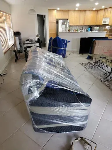 Blue sofa wrapped in plastic and padding, ready for moving, in a home.