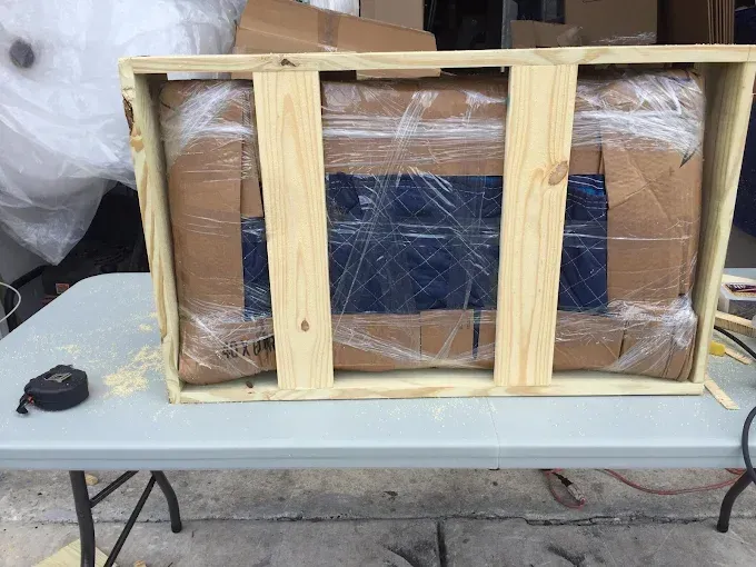 Wooden crate containing a wrapped package on a gray table.