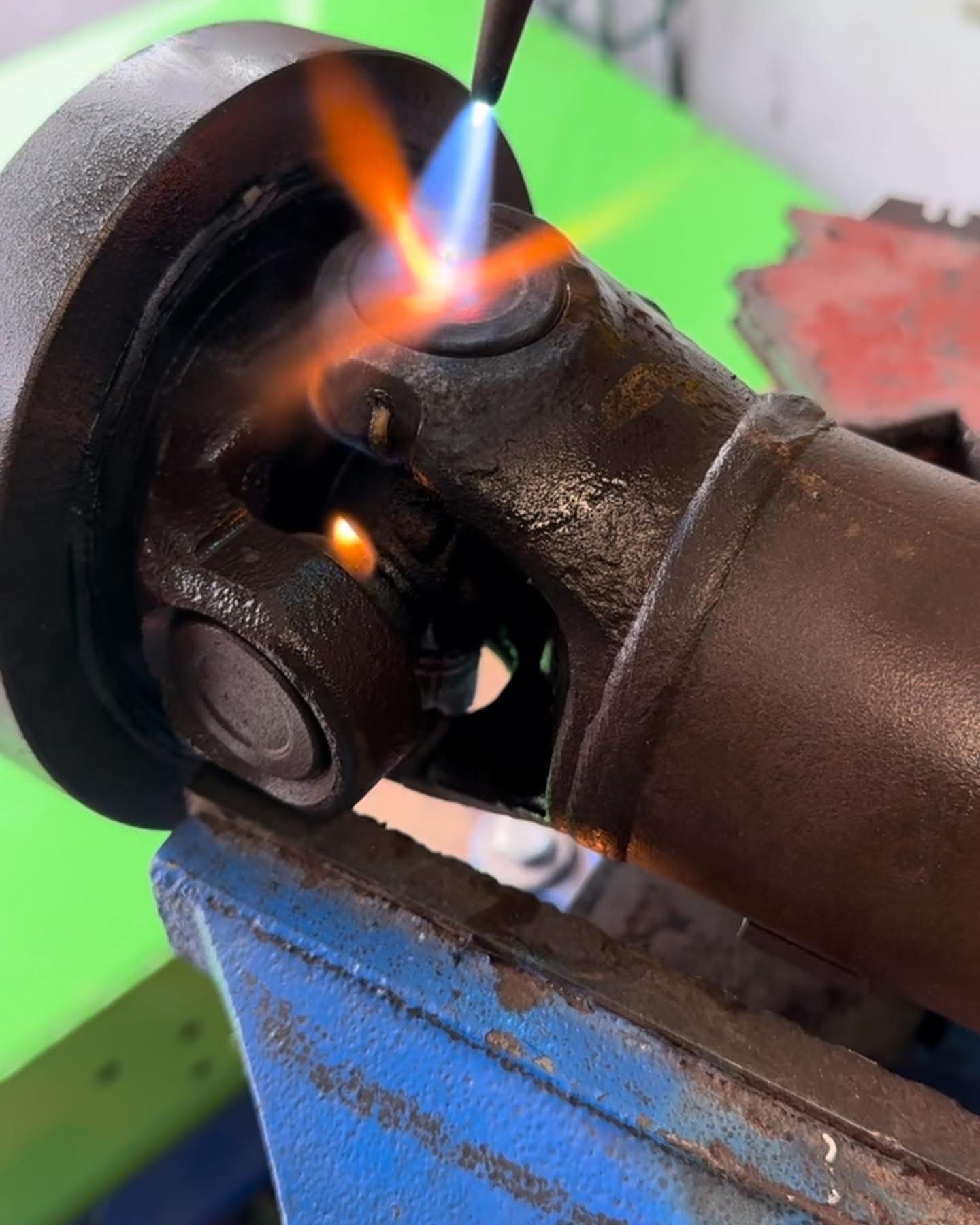 A torch heating a U-joint on a driveshaft held in a vise | 3T’s Mobile Automotive Repair Inc.