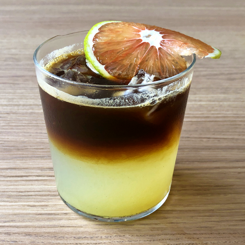 Una bebida en un vaso con una rodaja de naranja encima.