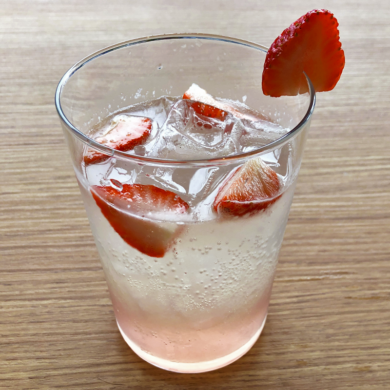 Un vaso de agua con fresas y hielo.