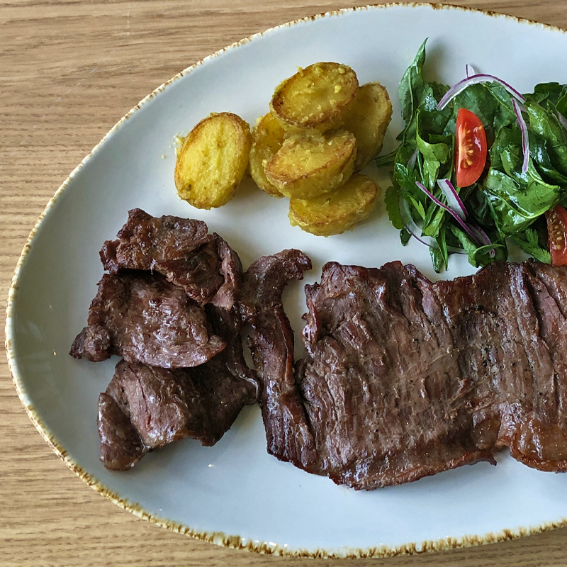 Un plato blanco cubierto con patatas fritas y ensalada.