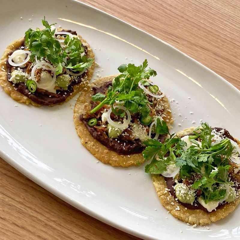 Un plato blanco cubierto con tres tortillas rellenas de carne y verduras.