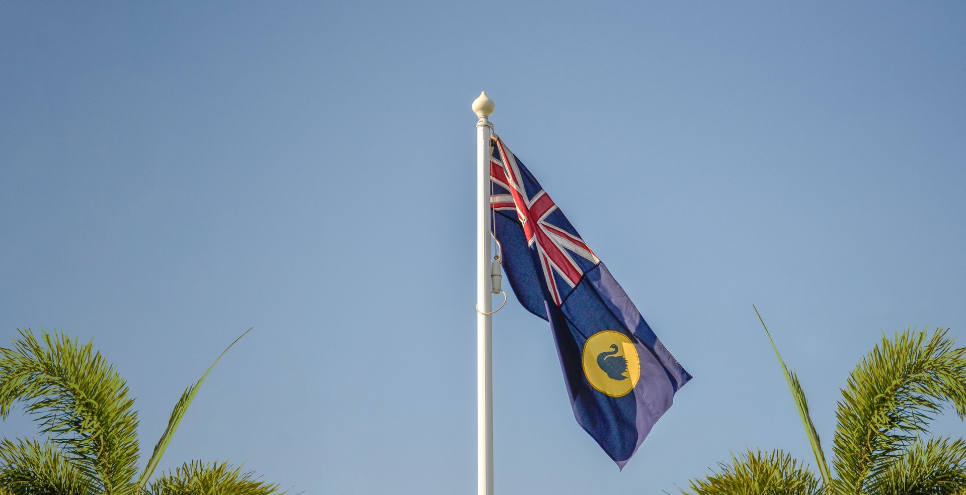 Gloved hand touching a red wire in an open electrical panel with multiple breakers and white wires.