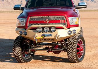 front view of red pickup truck on jacked wheels with gold front bumper and extra front spot lights