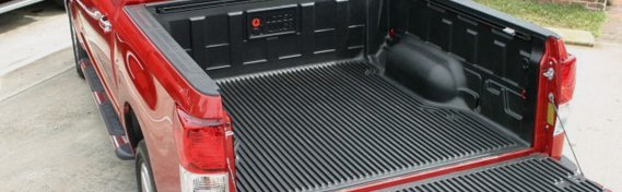 rear aerial view of black truck bed liner inside red pickup truck