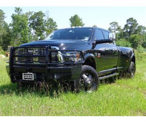 Large black pickup truck in grass with a black grill guard and front bumper