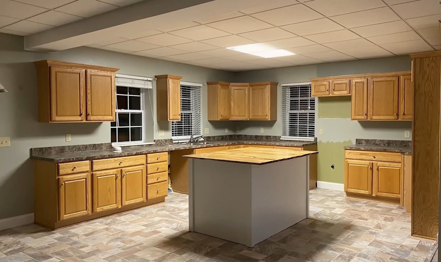 Kitchen with light wood cabinets, gray countertops, and a white island. 