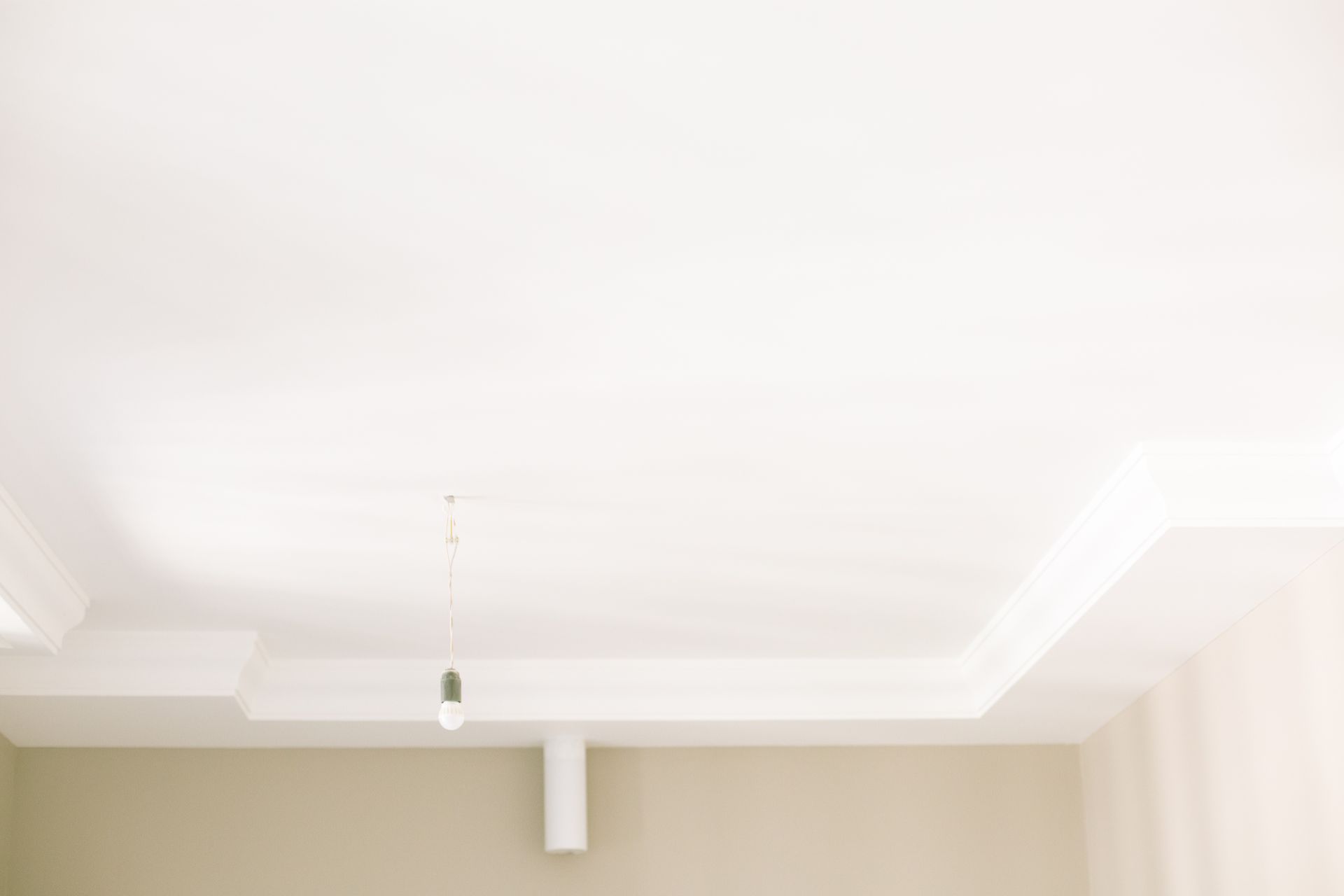 White ceiling with crown molding, a hanging light, and beige walls.
