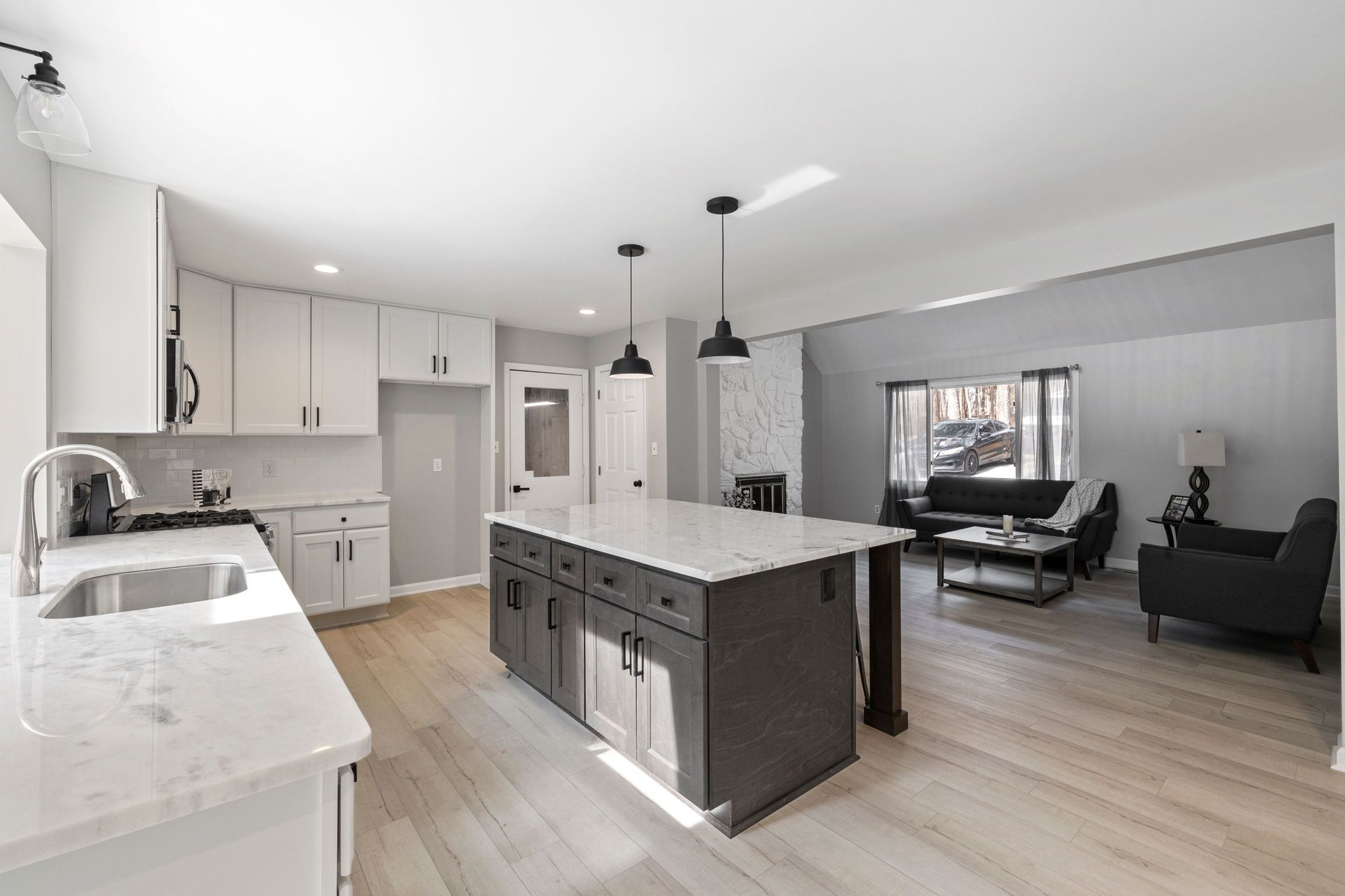 Modern kitchen with an island, cabinets, and a view into the living room.