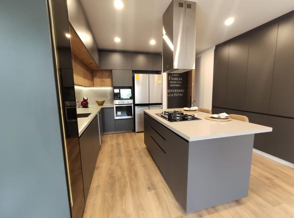 Cocina moderna con gabinetes grises, detalles de madera y una isla con estufa.