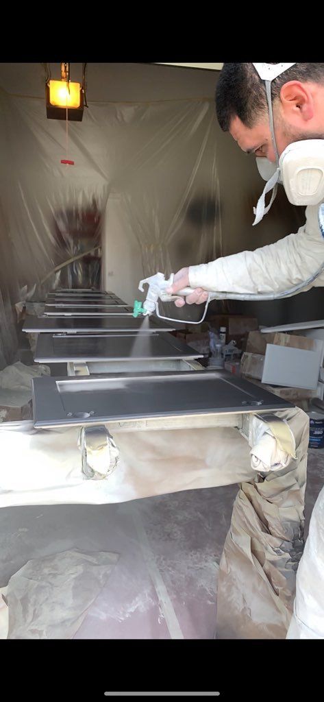 painter using sprayer to paint kitchen cabinets