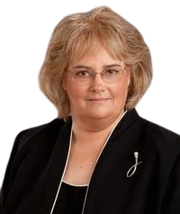 A woman wearing glasses and a black jacket is standing in front of a white background.