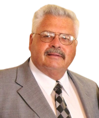 A man with glasses and a mustache is wearing a suit and tie