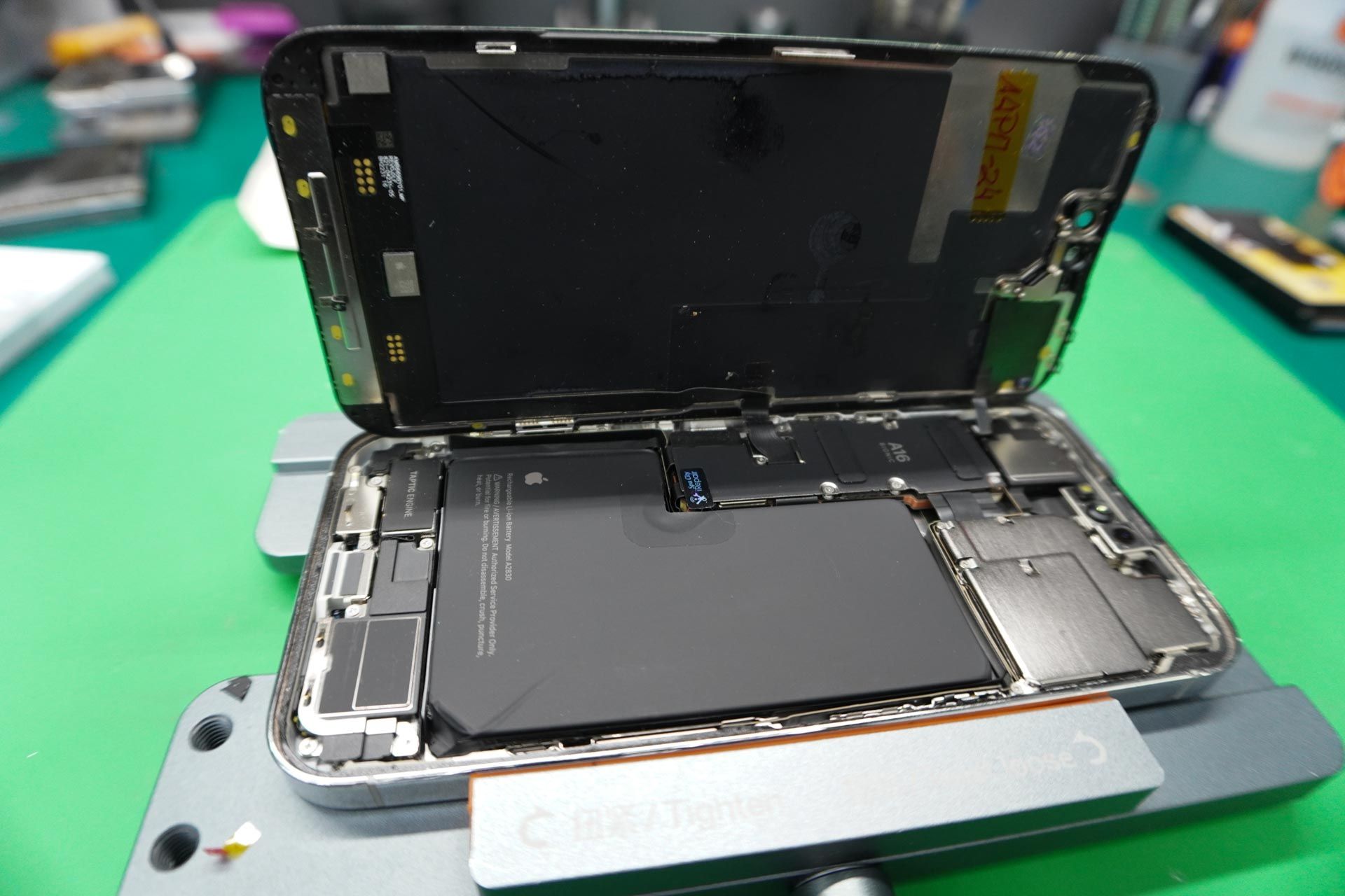 A cell phone is being disassembled on a green table.