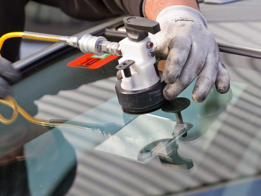 a person is repairing a windshield with a tool .
