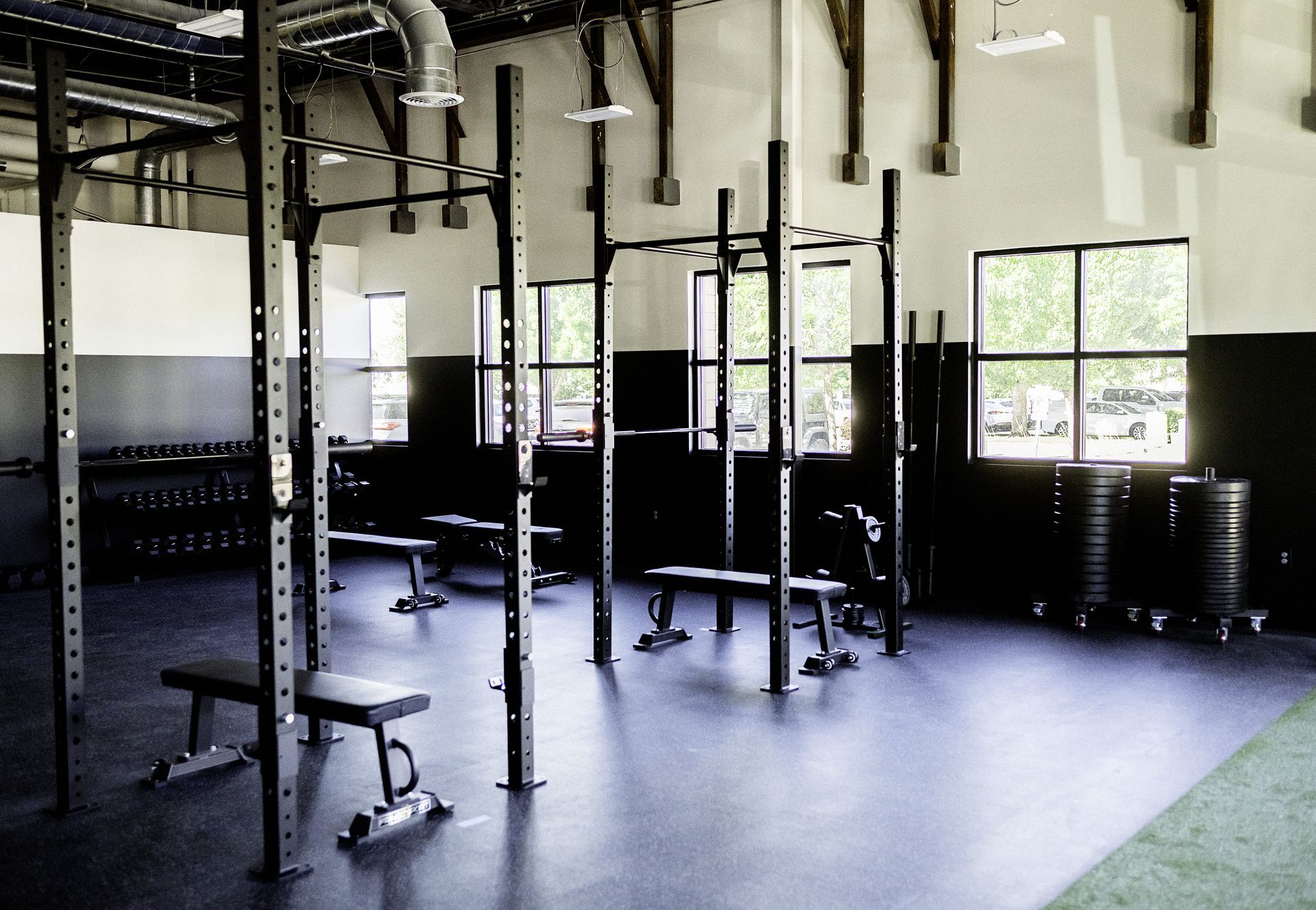 Gym interior with weightlifting racks, benches, and dumbbells.