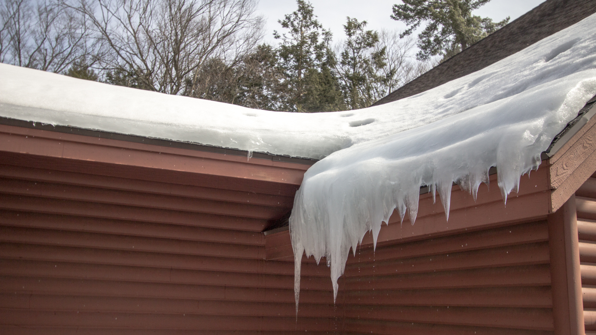 Icicles are hanging from the roof of a house.