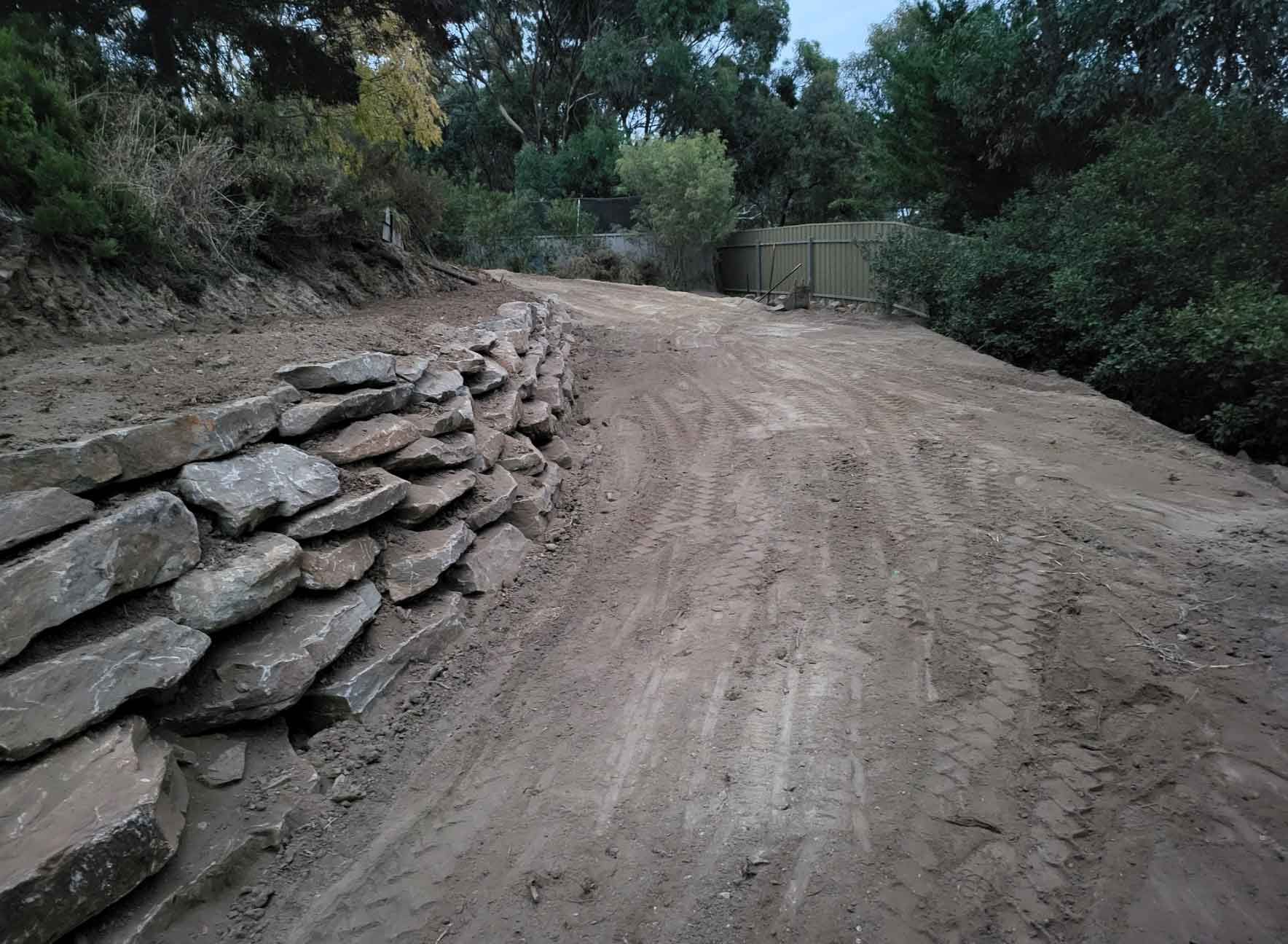 A Dirt Road With A Stone Wall On The Side Of It – Blackwood SA - Blackwood Earthmoving
