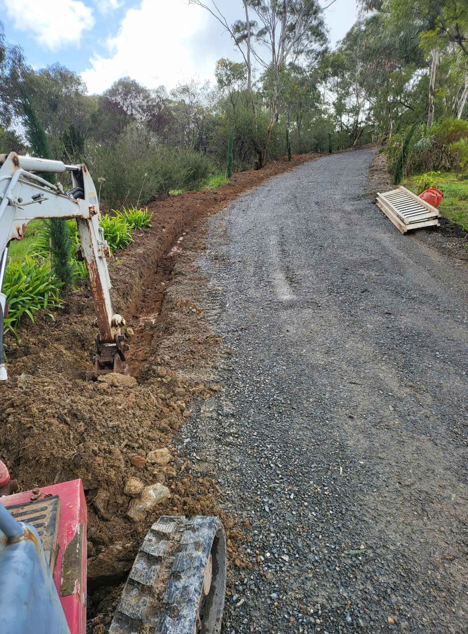 A Person Is Driving A Small Excavator Down A Dirt Road – Blackwood SA - Blackwood Earthmoving