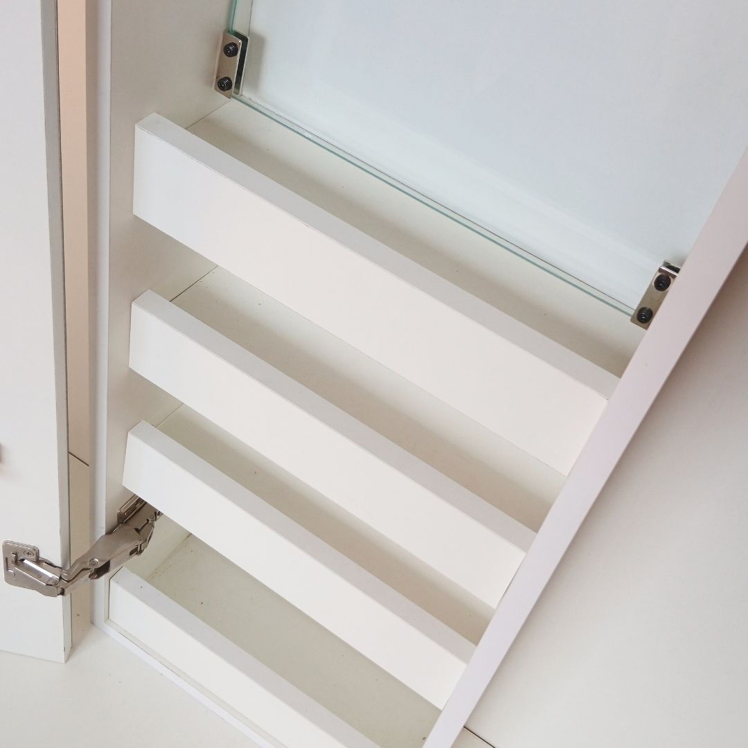 Puerta de armario plegable blanca con listones horizontales y detalle de bisagra metálica, mostrada en primer plano desde un ángulo.