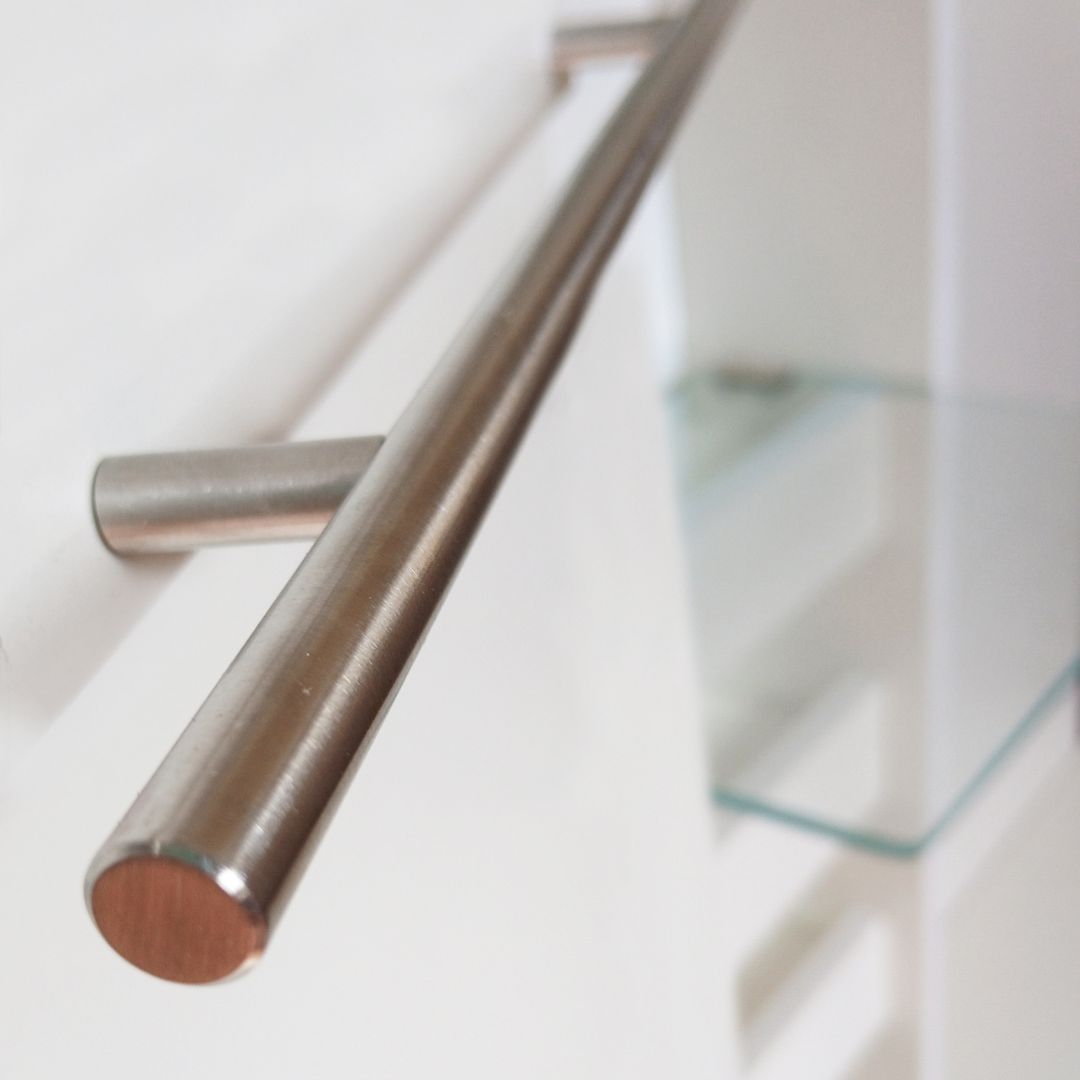 Barandilla de acero inoxidable montada sobre una pared blanca de la escalera con detalles de vidrio.