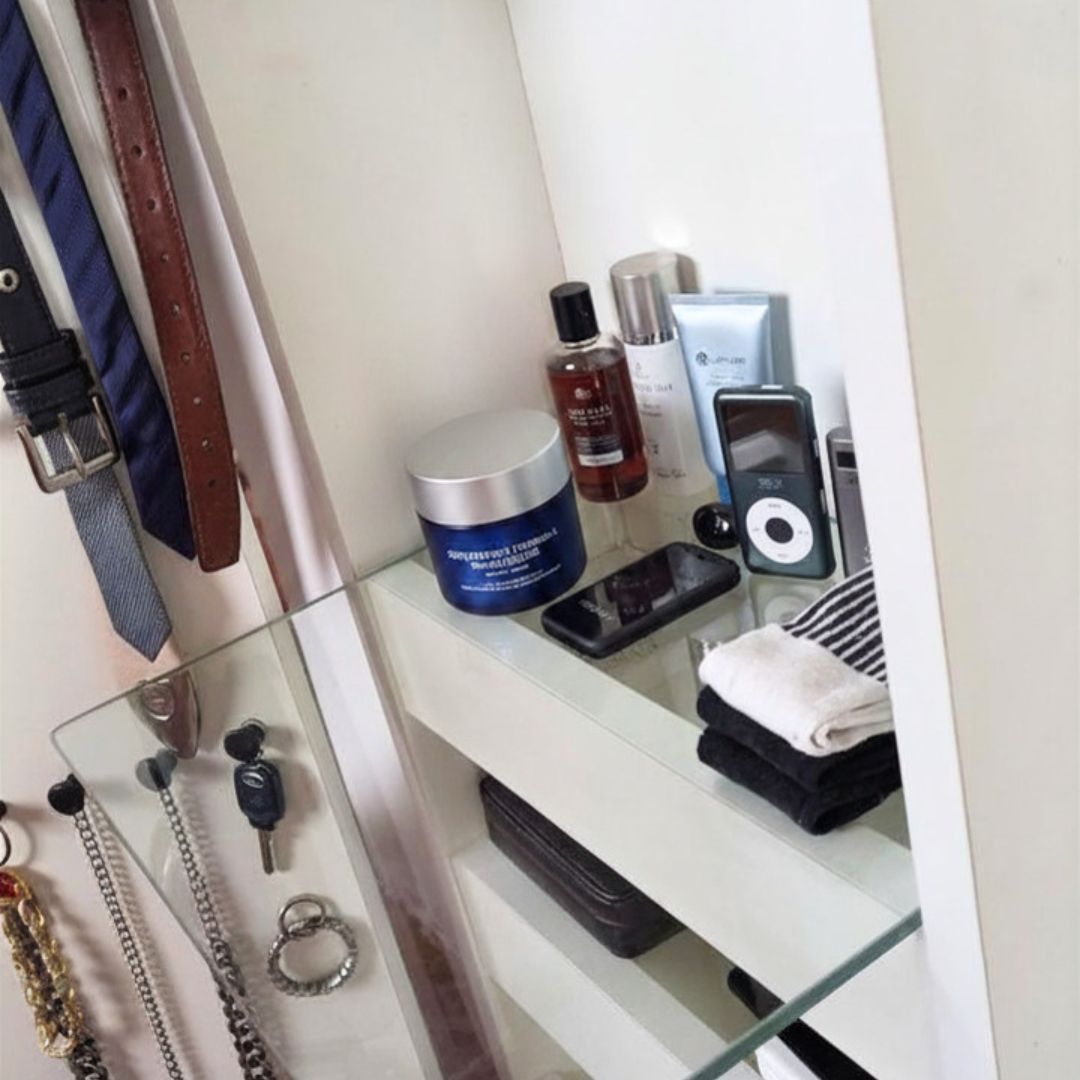 Cosmeticos y productos de cuidado masculino apoyados en bandeja de tocador. Corbatas, cintos y collares de hombre colgados