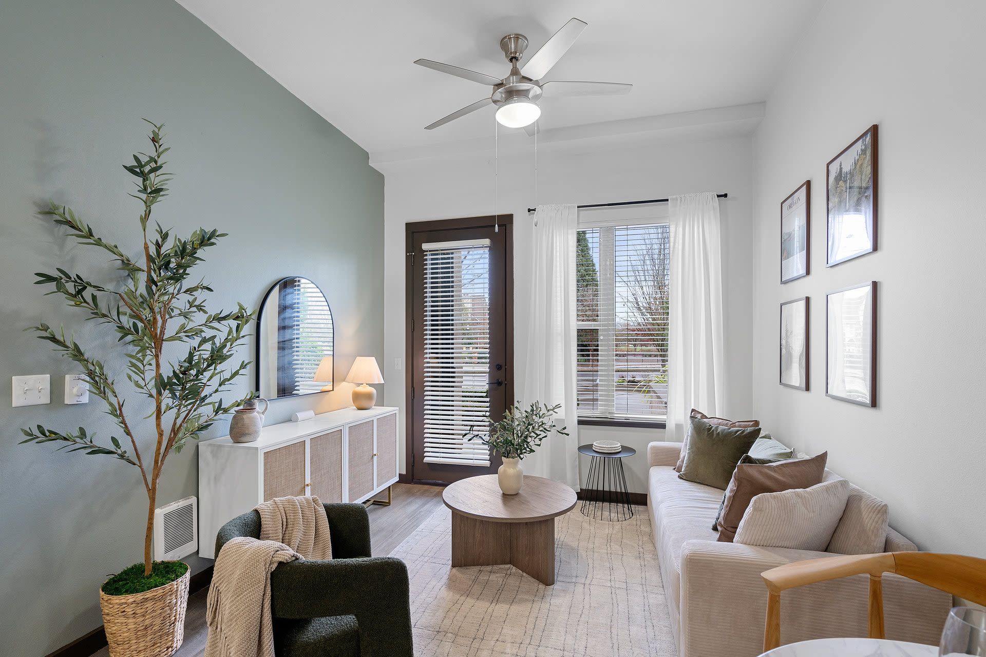 Living room in an apartment with a green accent wall, sofa, coffee table, and plants.