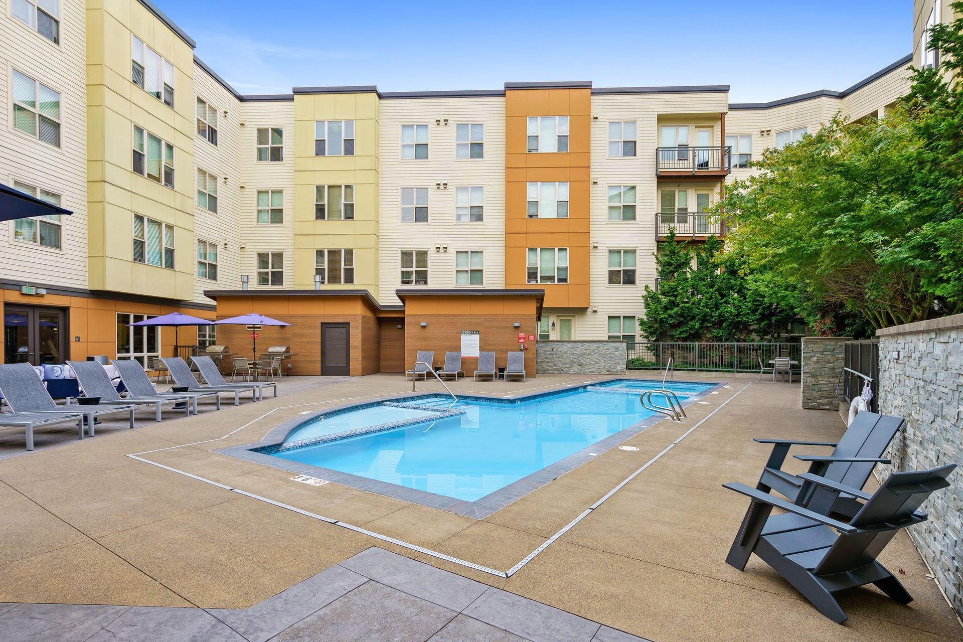 Outdoor apartment pool with lounge chairs and umbrellas in a courtyard