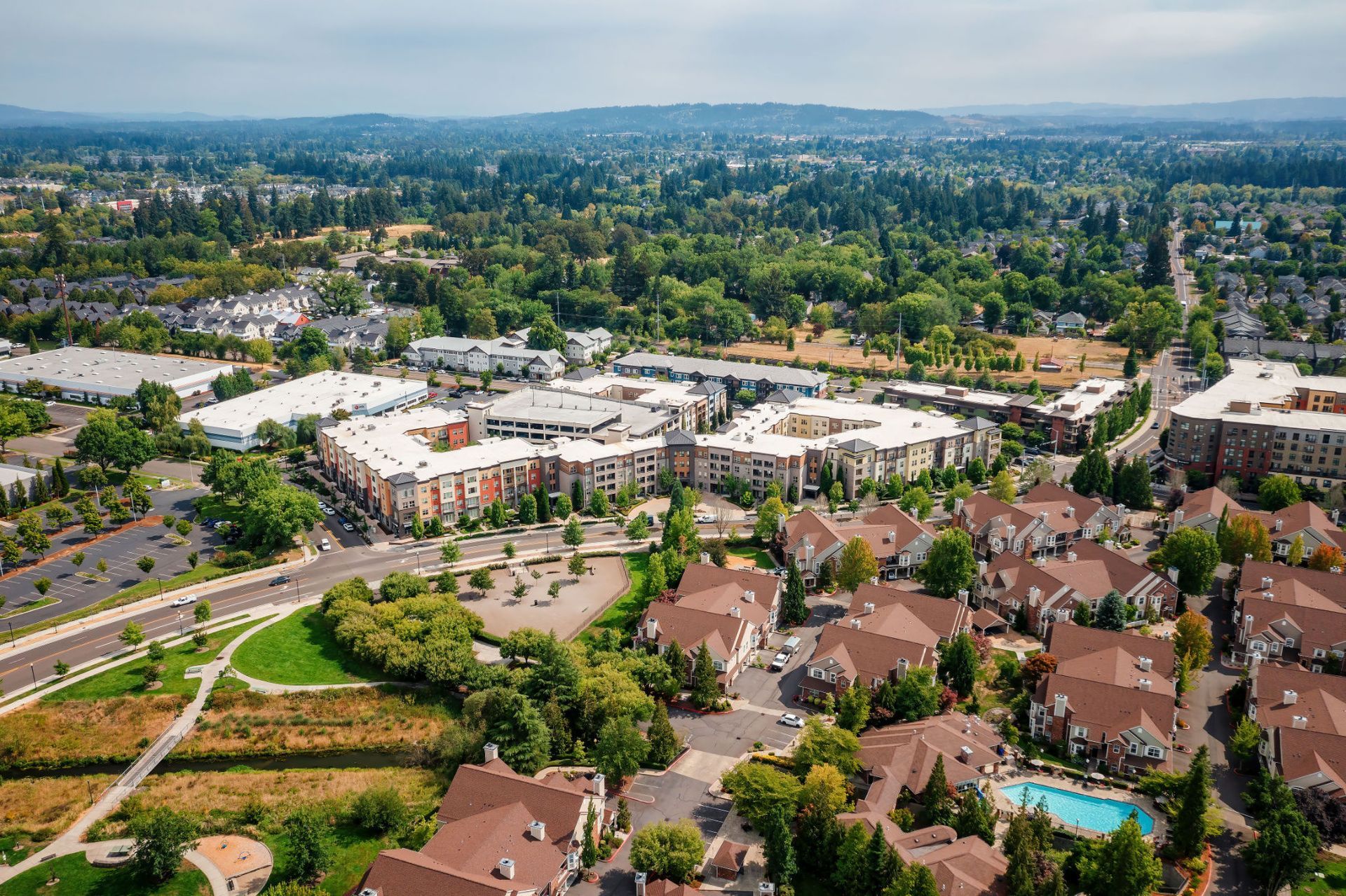 Aerial view of a suburban multifamily community with interconnected mid-rise buildings and a visible pool.
