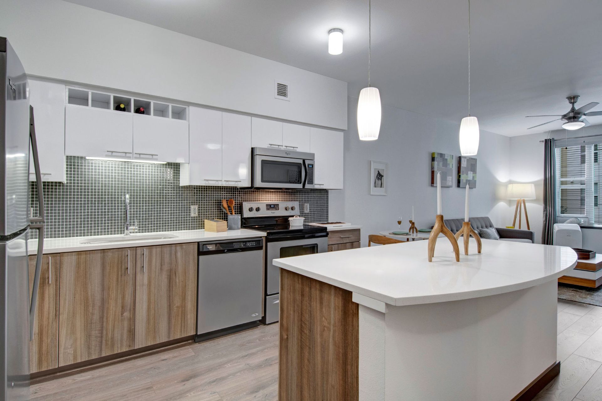 Modern apartment kitchen with white cabinets, stainless appliances, and a large island.