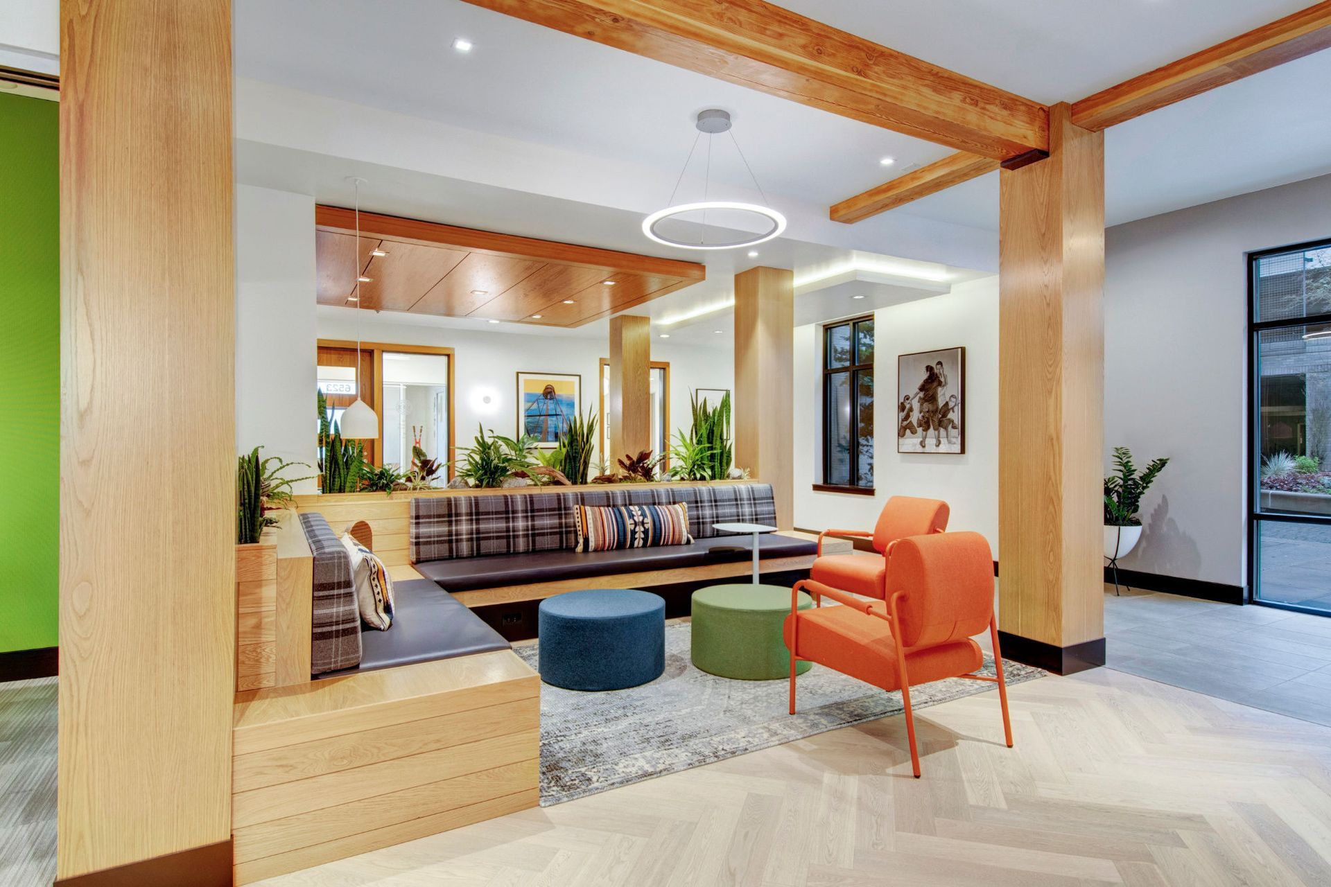 Modern apartment community lounge with wooden beams, plants, and colorful seating.