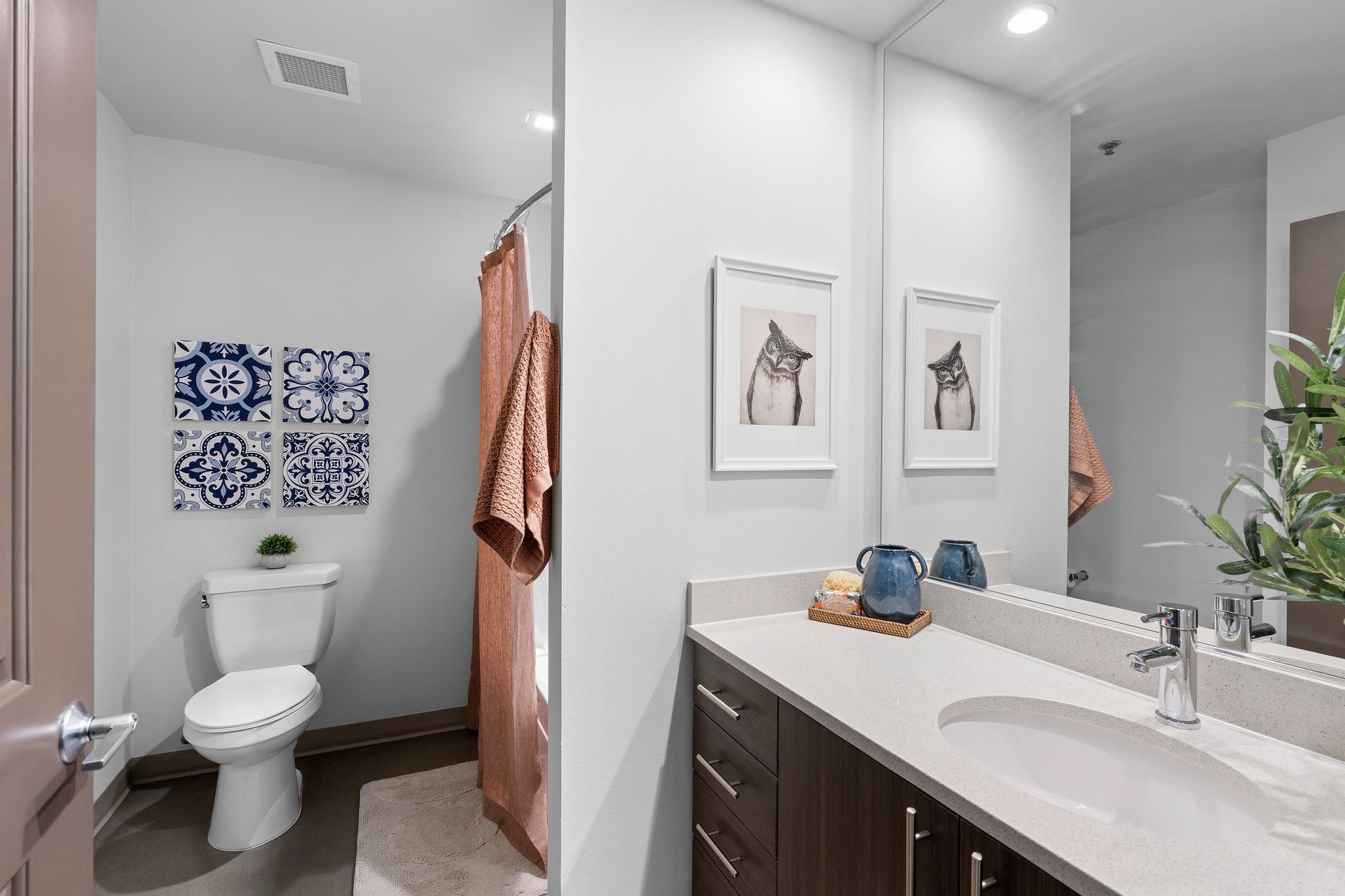 Apartment bathroom with a single vanity, sink, mirror, toilet, and pink shower curtain.