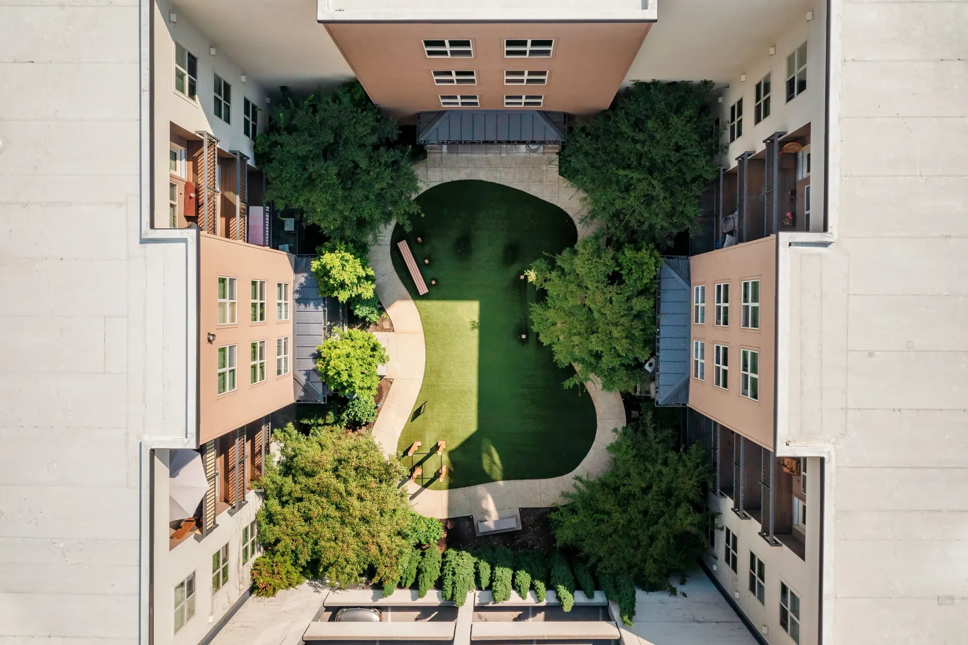 Aerial view of a courtyard between apartment buildings with trees and a green lawn.