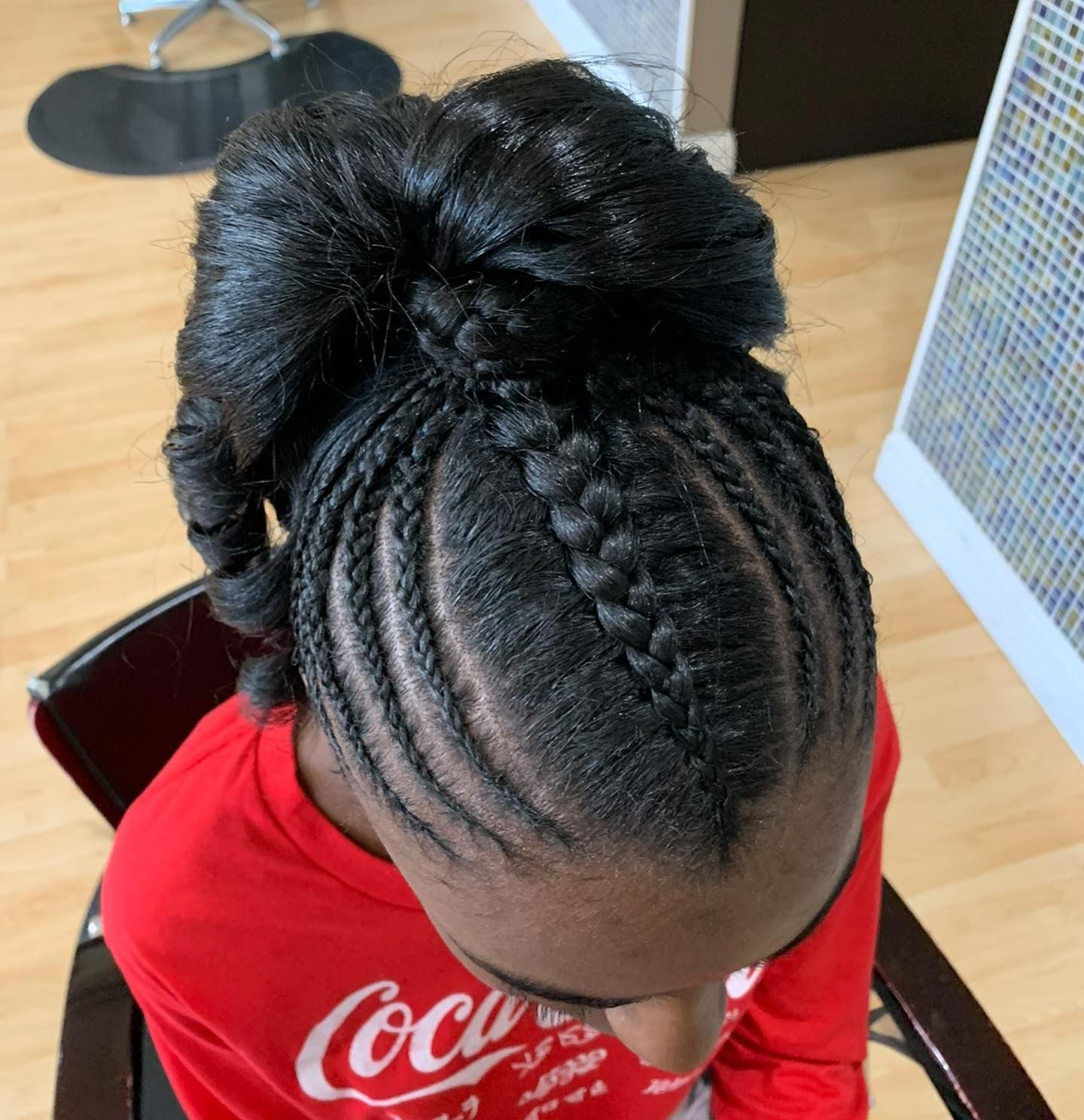A person wearing a red coca cola shirt with braids in their hair