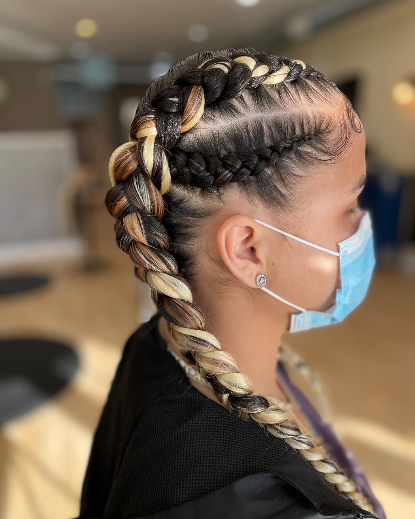 A woman wearing a mask and braids in her hair.