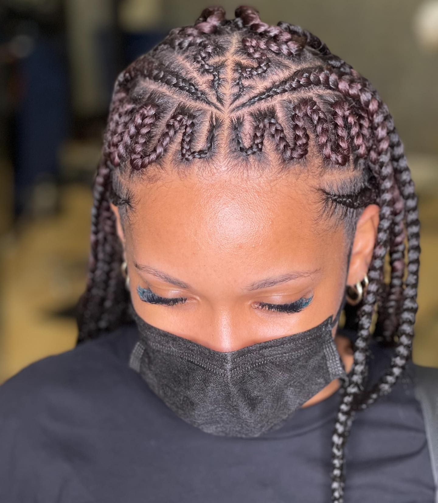 A woman wearing a black mask with braids in her hair.