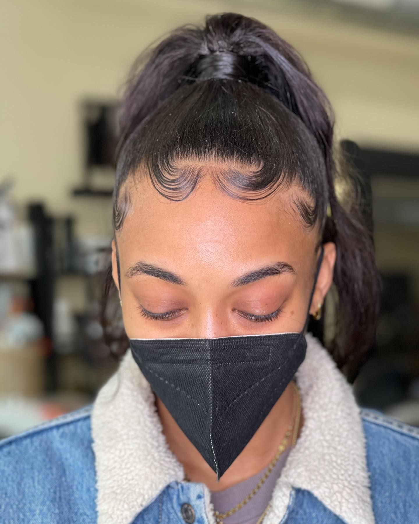 A woman wearing a black face mask and a ponytail.