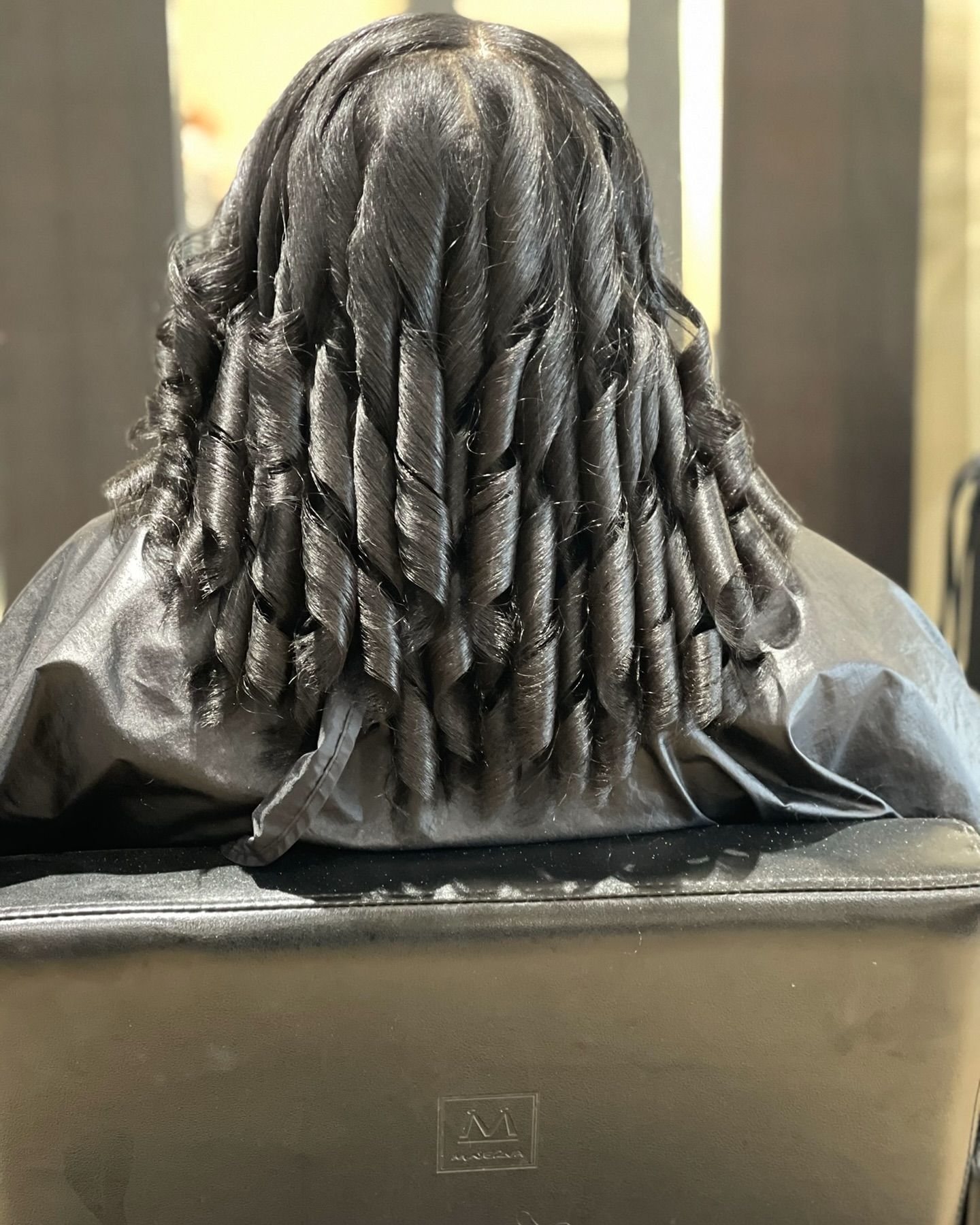 A woman is sitting in a chair with her hair in a bucket.