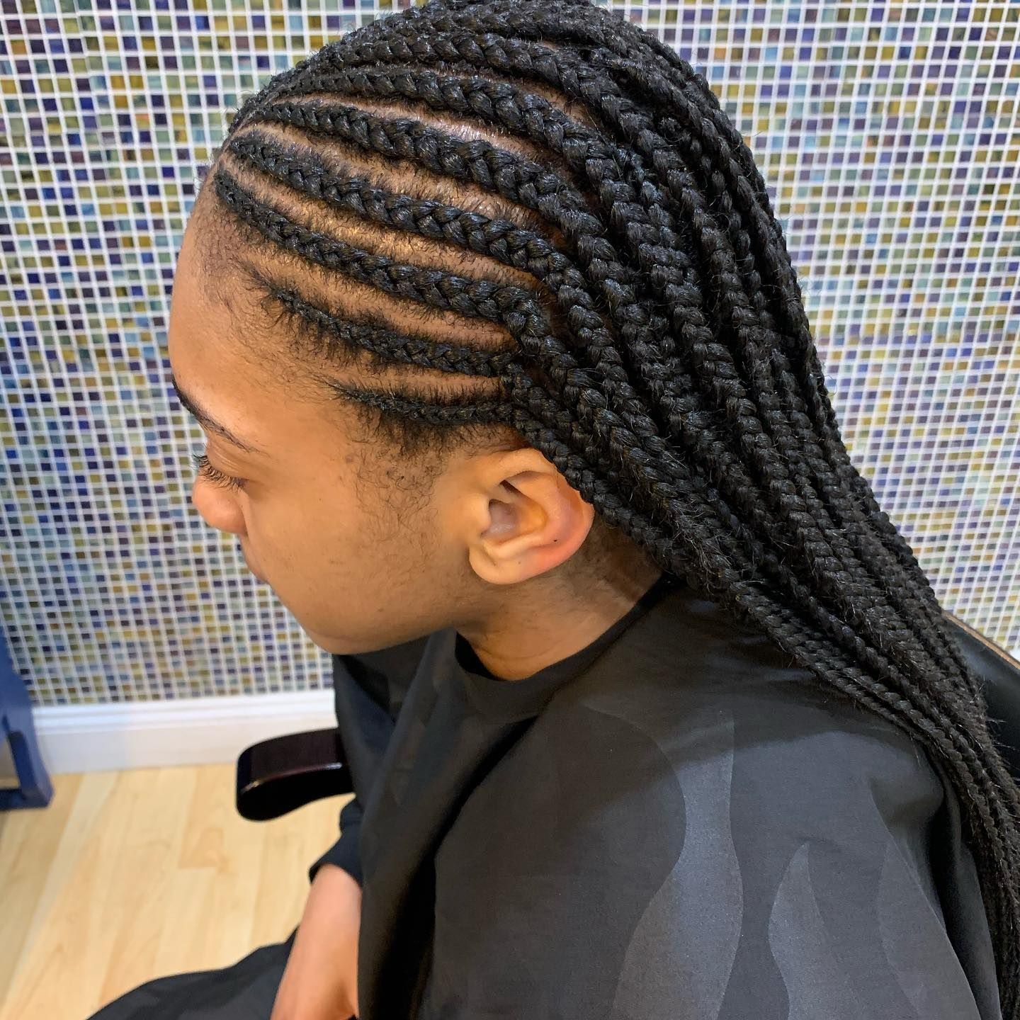 A woman is sitting in a chair with braids in her hair.