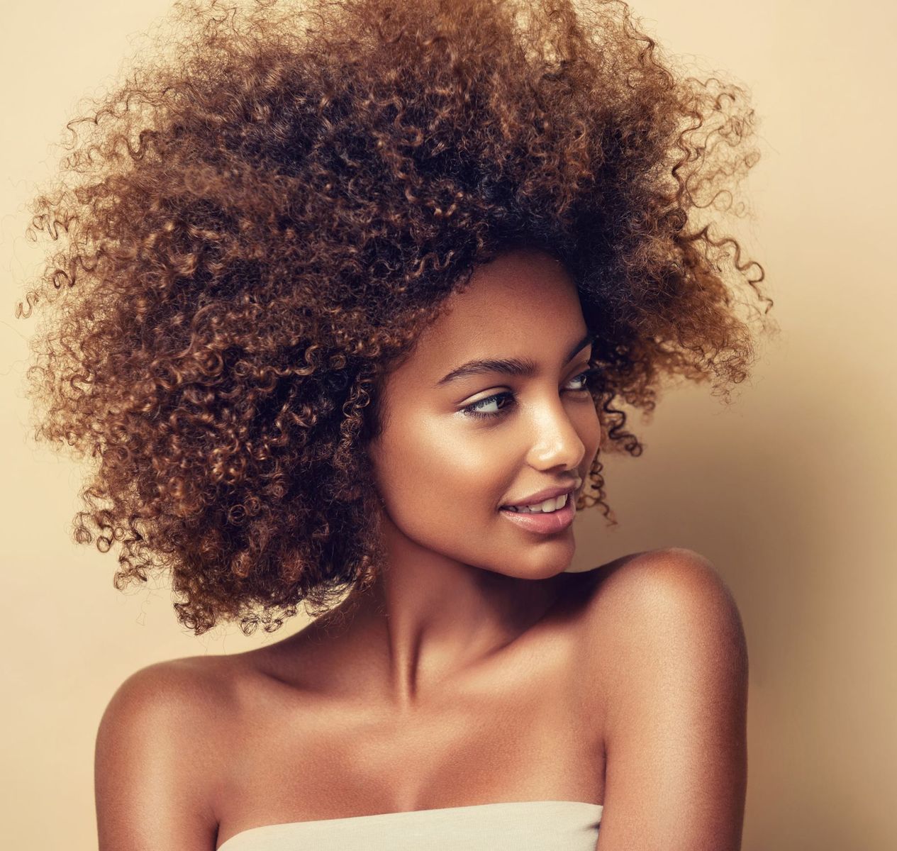 A woman with curly hair is wearing a white strapless top
