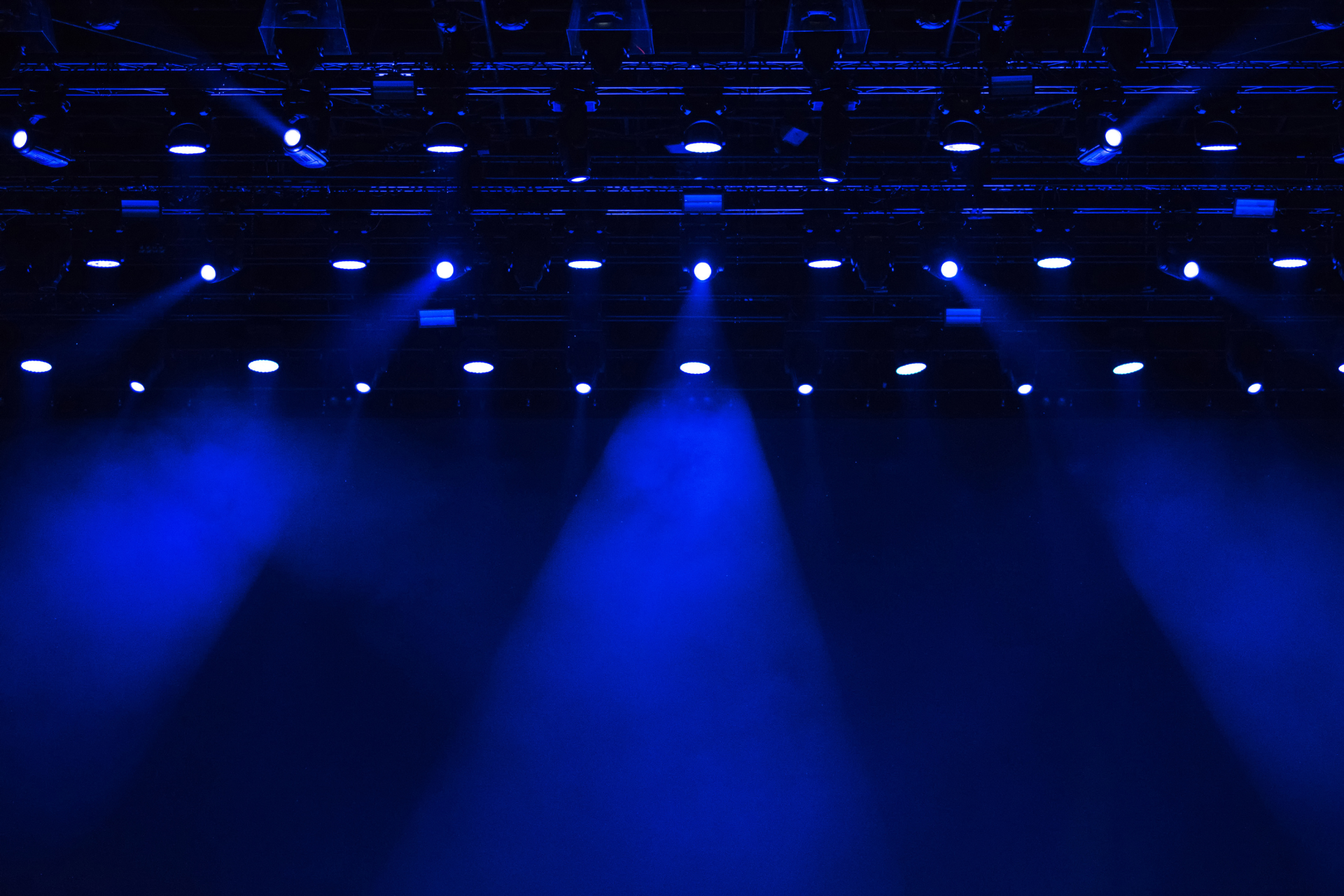 Blue stage lights shining over a dark empty stage