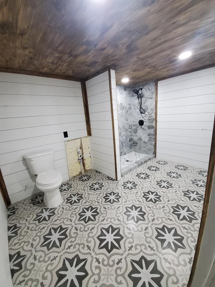 A bathroom with a toilet , shower and tile floor.