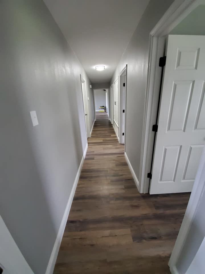A long hallway in a house with hardwood floors and gray walls.