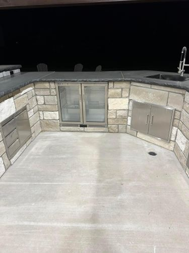 A large outdoor kitchen with stainless steel cabinets and a sink.