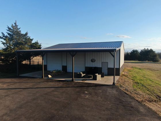 A white building with a blue roof sits in the middle of a field