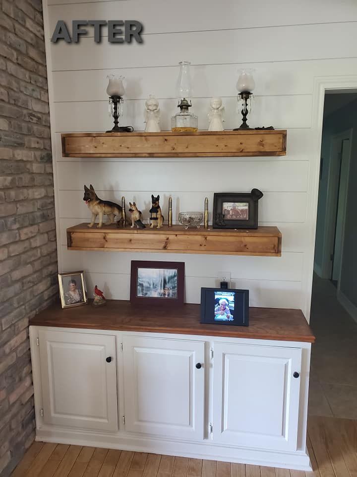 A living room with a brick wall and a shelf with pictures on it.